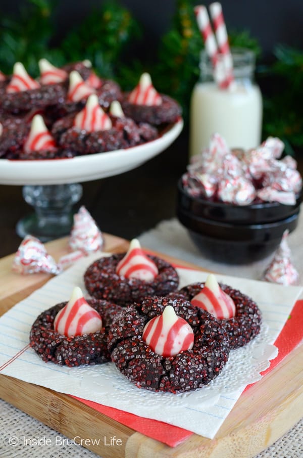 Chocolate candy cane kiss with sugar on a white napkin and more cookies behind it.