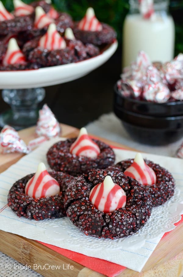 A white napkin with chocolate candy cane kiss cookies rolled in red and white sugar on it.