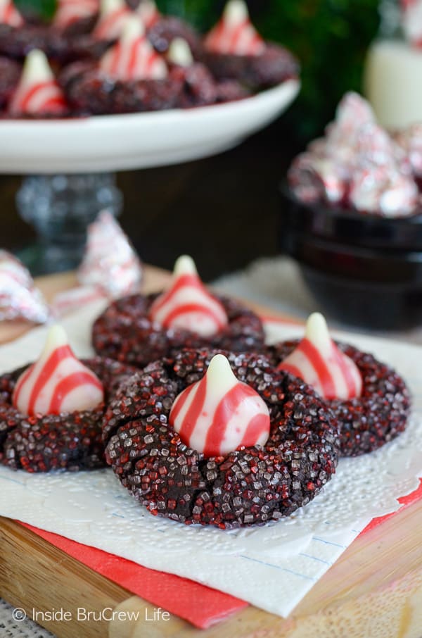 A close up of a chocolate kiss cookie rolled in sugar and topped with a candy cane kiss.