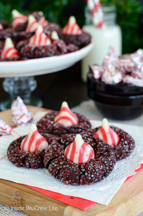 Four chocolate kiss cookies rolled in red and white sugar and topped with a candy cane kiss.