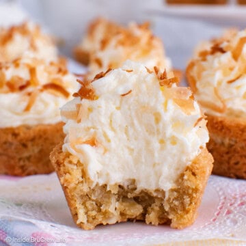 Coconut cream cookie cups on a gray board with a bite out of the front cookie.