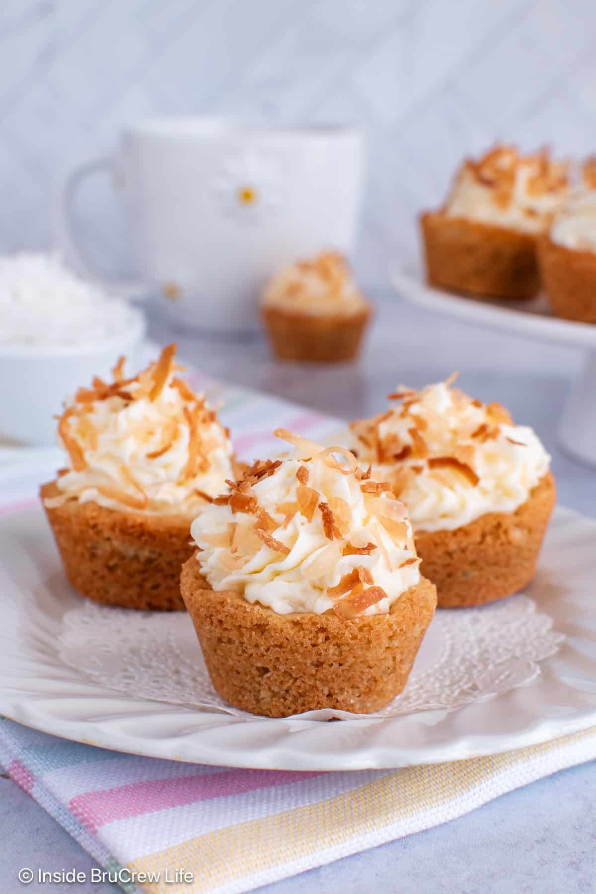 Three coconut cream pie cookie cups on a white plate.