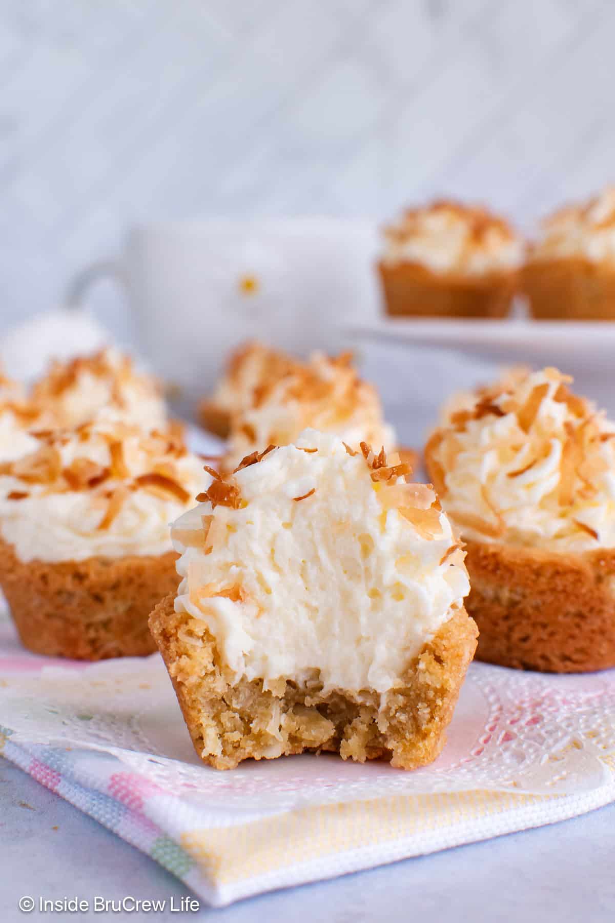 Coconut cream cookie cups on a gray board with a bite out of the front cookie.