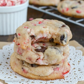 Three Oreo peppermint crunch cookies stacked on a white doily with a bite taken out of the top cookie