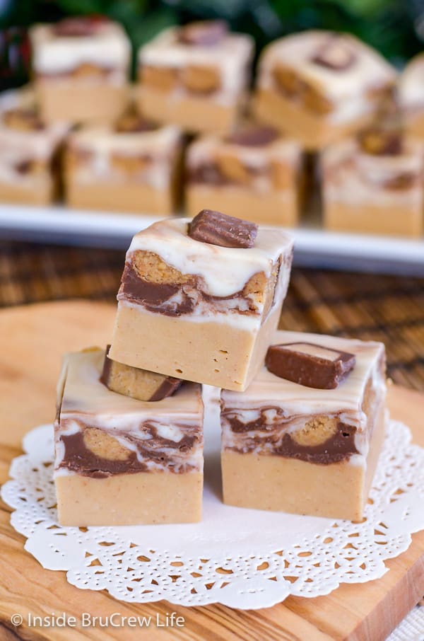 3 pieces of White Chocolate Peanut Butter Cup Fudge with more fudge in the background. 