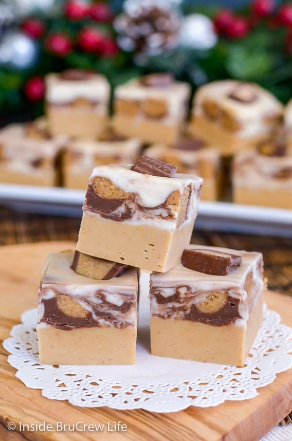 3 pieces of White Chocolate Peanut Butter Cup Fudge on a white doily.