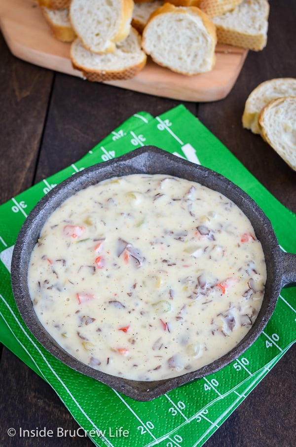 An overhead picture of cheesy dip in a skillet on a football field napkin.