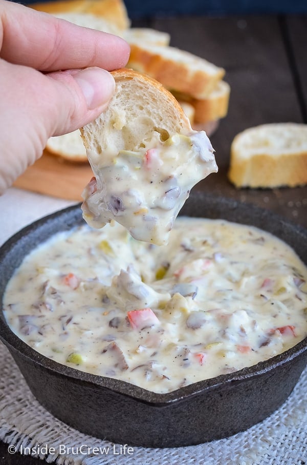 Close up picture of bread dipped into cheesy queso dip.