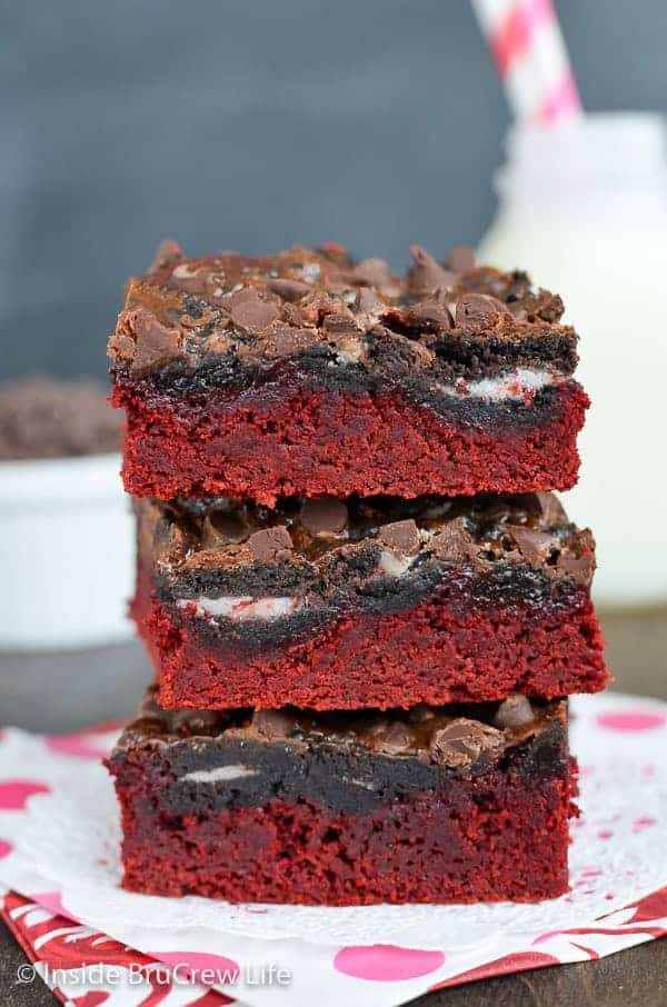 Three red cake bars topped with chocolate chips stacked on top of each other.