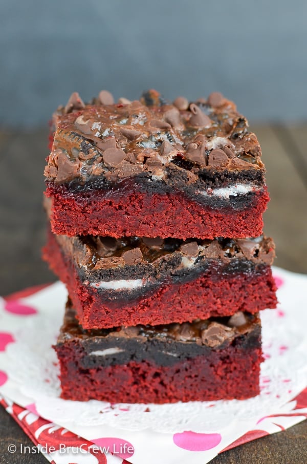 A stack of three red velvet cake bars with Oreos and chocolate on top.