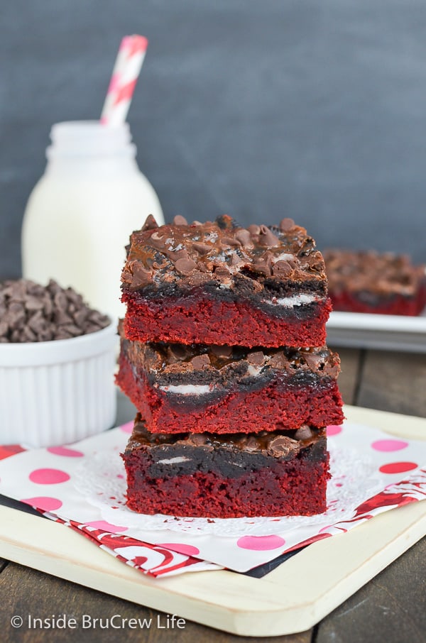 A stack of three red velvet bars with Oreos and chocolate chips on them.