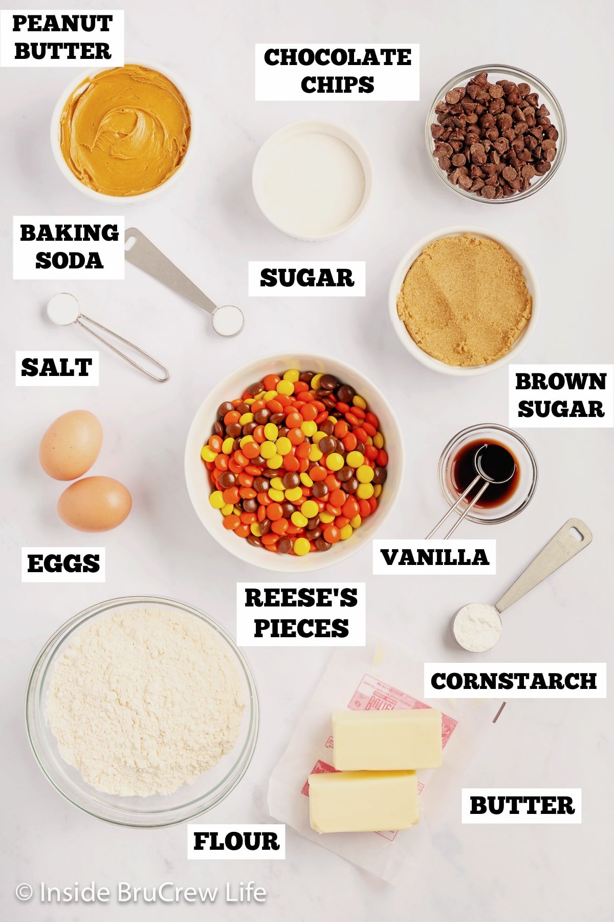 A white board with bowls of ingredients needed to make peanut butter cookies with candies.