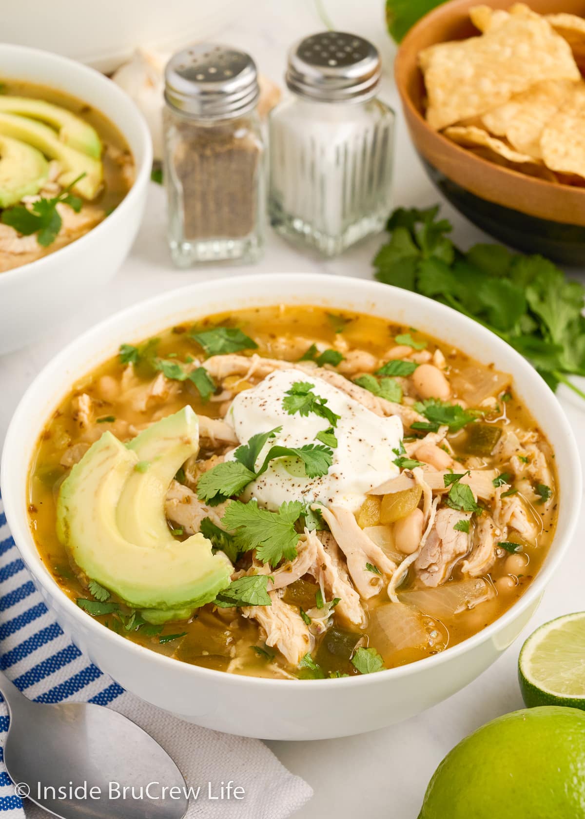 A white bowl filled with chicken chilii and toppings.