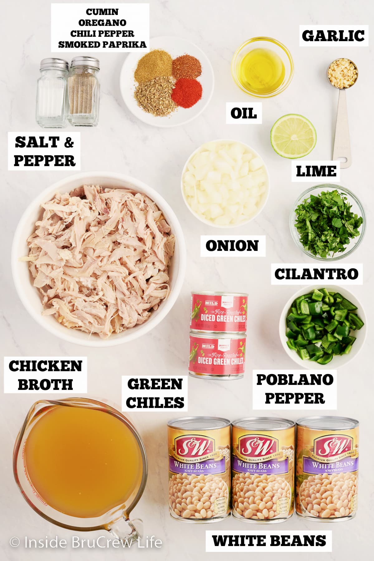 A white board with bowls of ingredients needed for chicken chili.