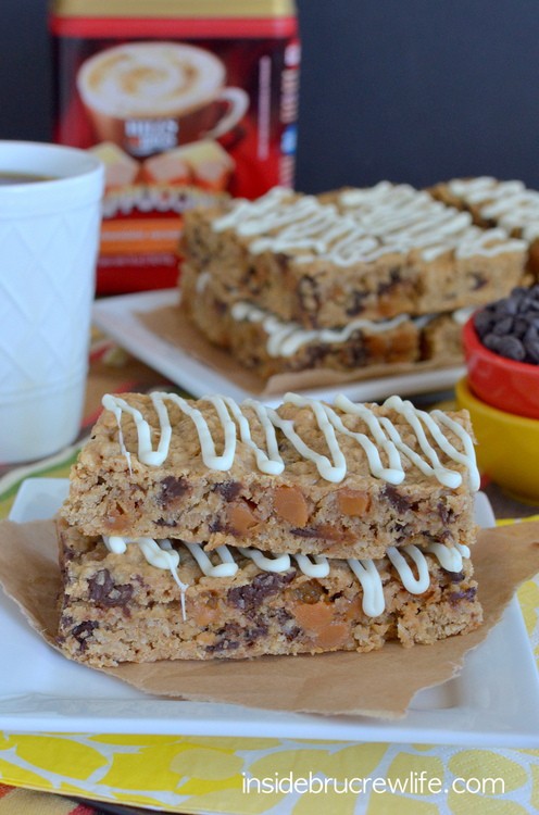 A white plate with white chocolate caramel granola bars stacked on it and more bars behind it