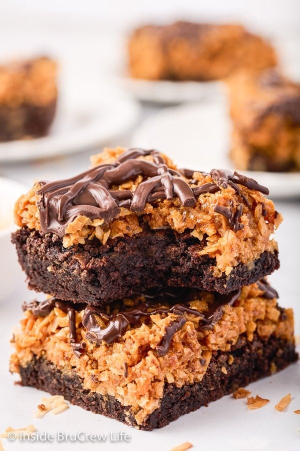 Two brownies with a caramel coconut layer stacked on top of each other.