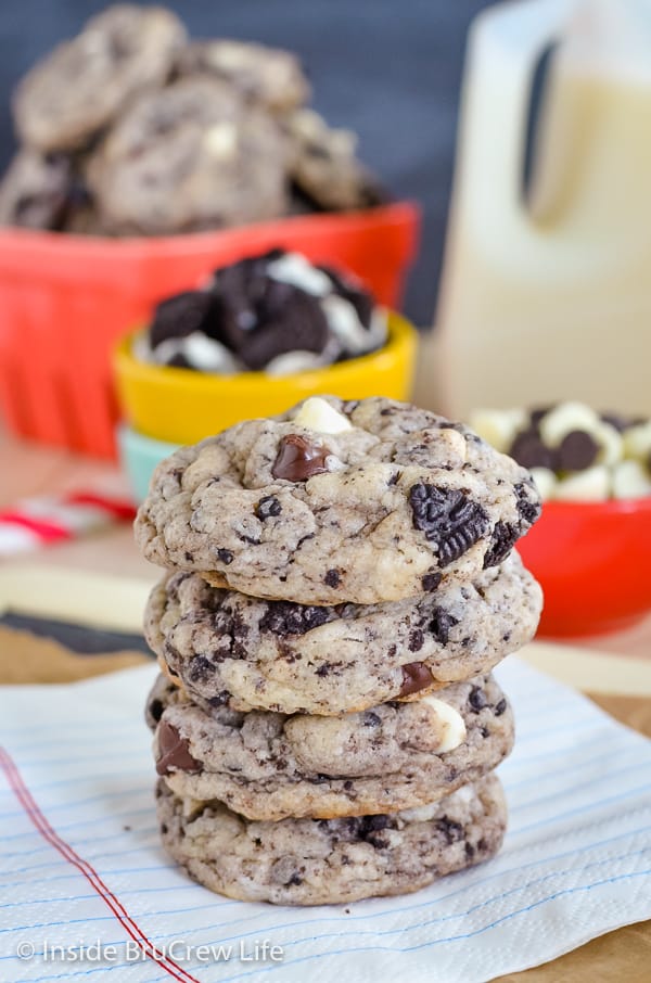 Four chocolate chip cookies and cream cookies stacked up on a white striped napkin.