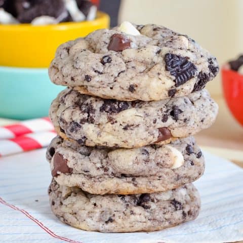 A stack of four chocolate chip cookies and cream cookies on a white napkin.