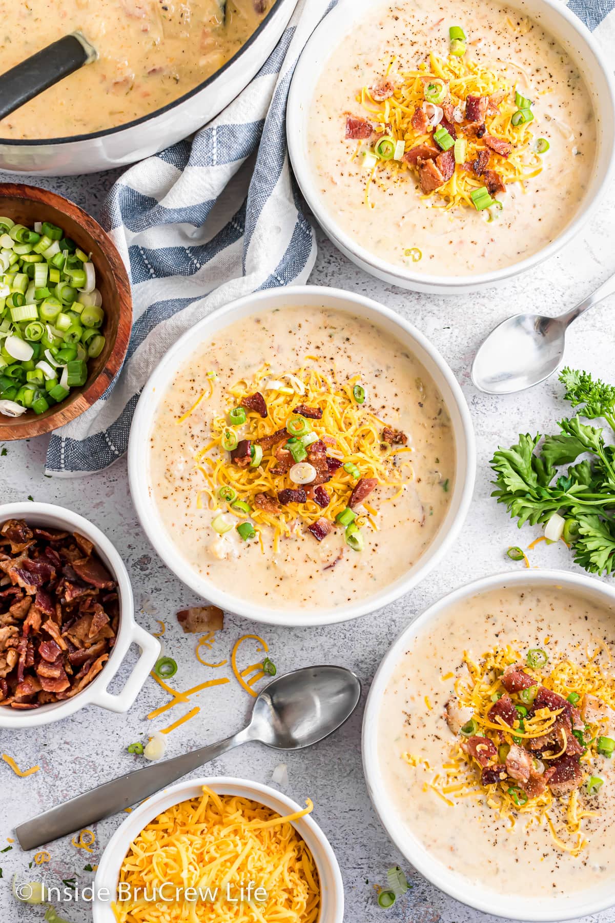 Three bowls of potato soup loaded with toppings.