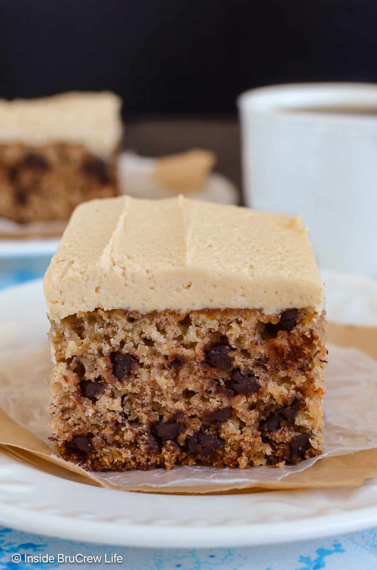 A white plate with a piece of banana sheet cake with chocolate chips on it.