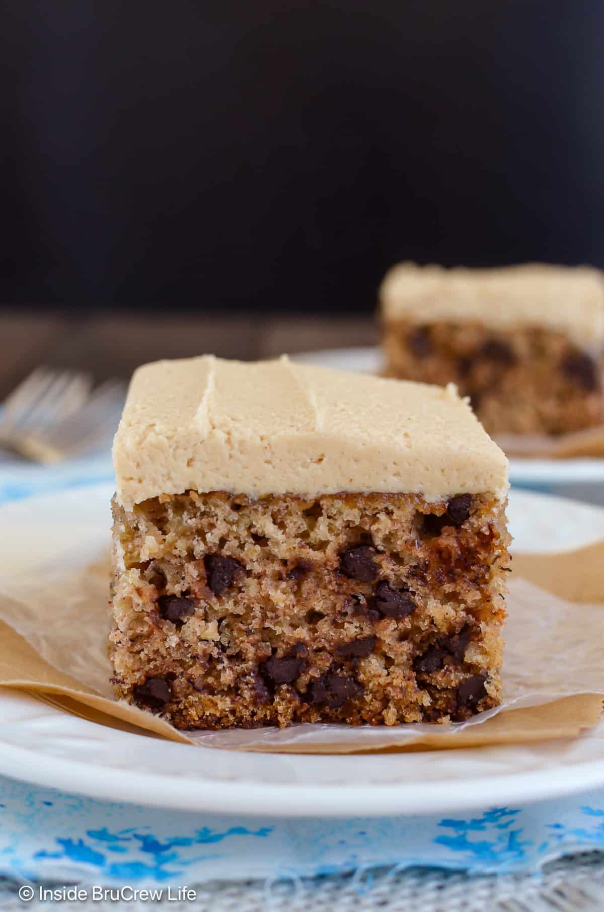 Two white plates with pieces of chocolate chip banana sheet cake on them.