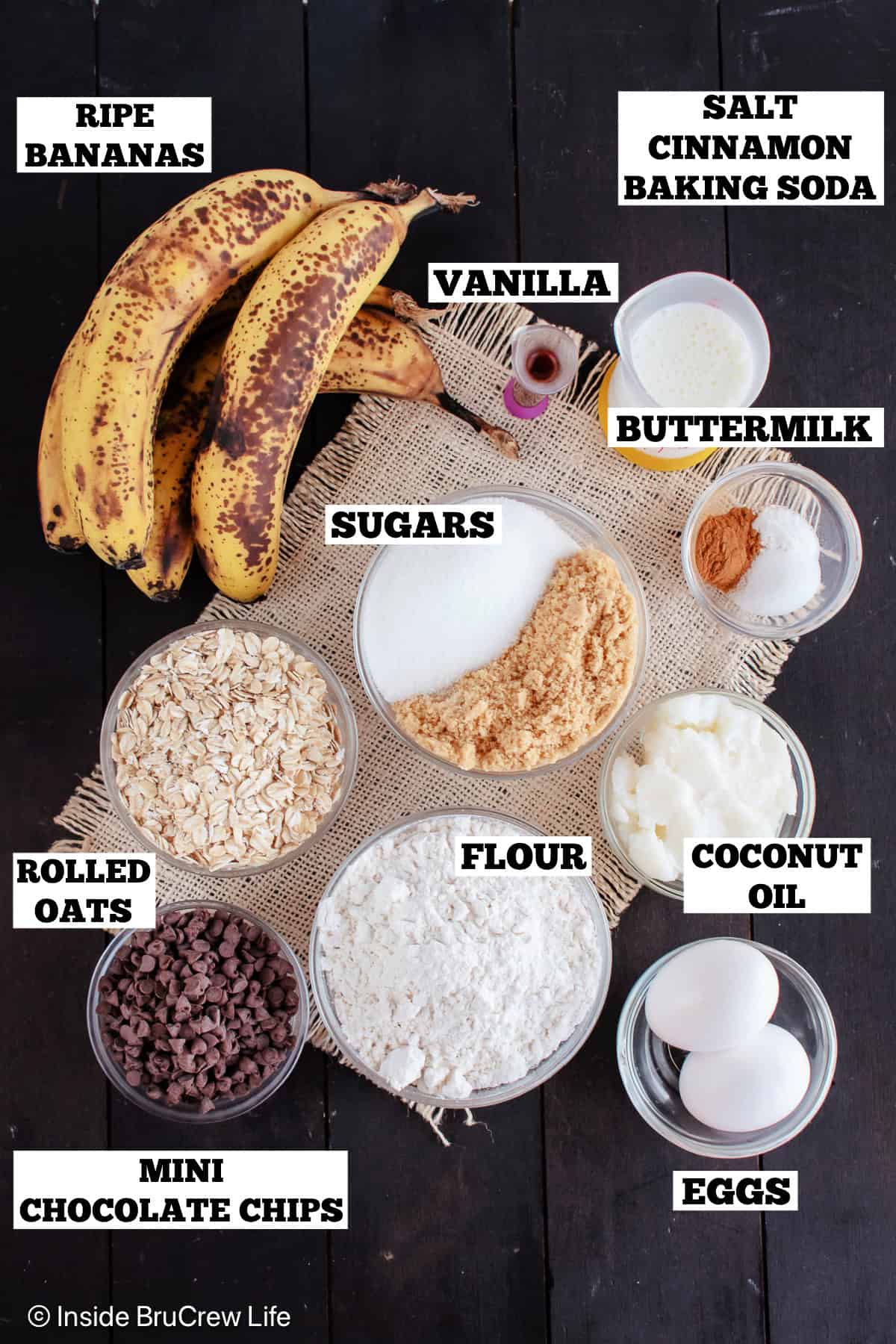 Ingredients for a banana sheet cake on a dark wood board.