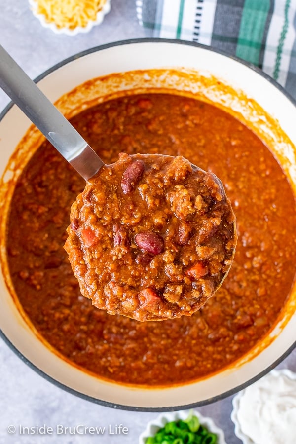 Overhead picture of a pot of Dr. Pepper Chili with a ladle lifting out a big scoop