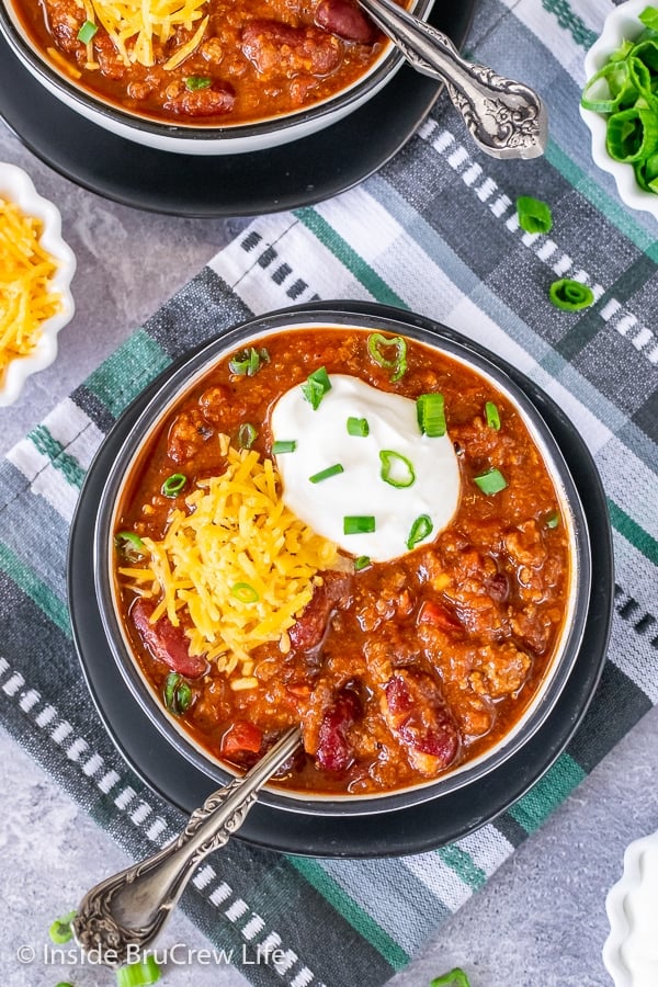 Overhead picture of the top of a bowl filled with Dr. Pepper chili and topped with sour cream, shredded cheese, and green onions