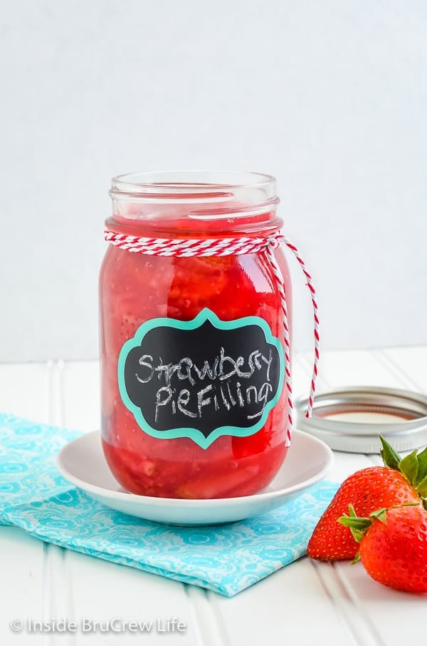 A large canning jar filled with homemade strawberry pie filling with a black label on the front.