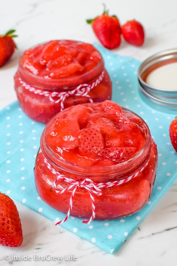 Two jars with red and white twine around them and filled with homemade strawberry pie filling.