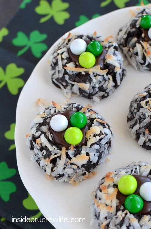 Chocolate cookies with toasted coconut on them on a white plate.