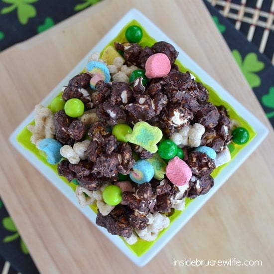 Chocolate popcorn mixed with Lucky Charms in a green square container.