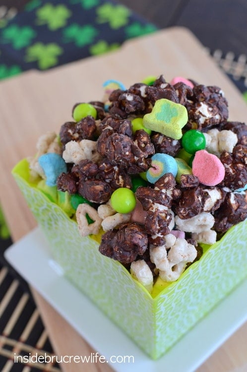 Chocolate popcorn mixed with Lucky Charms in a green square container.