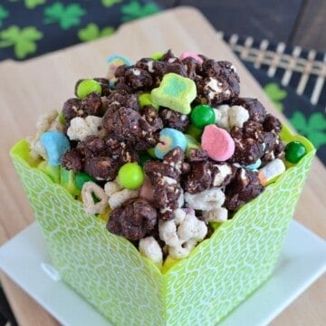 Chocolate popcorn mixed with Lucky Charms in a green square container.