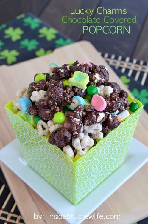 Chocolate popcorn mixed with Lucky Charms in a green square container.