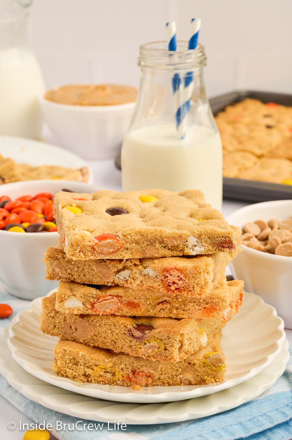 A stack of peanut butter bars with Reese's pieces on a white plate.