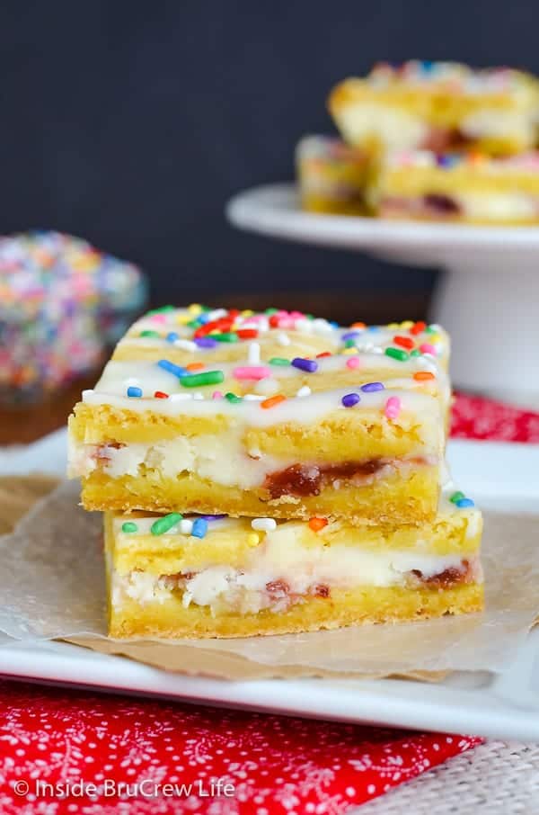 Strawberry Cheesecake Lemon Bars - a creamy cheesecake center with strawberry jelly makes these lemon bars so delicious. Try this cake mix recipe the next time you need an easy dessert. #lemon #lemonbars #cakemixrecipes #springdessert #cheesecake #strawberry