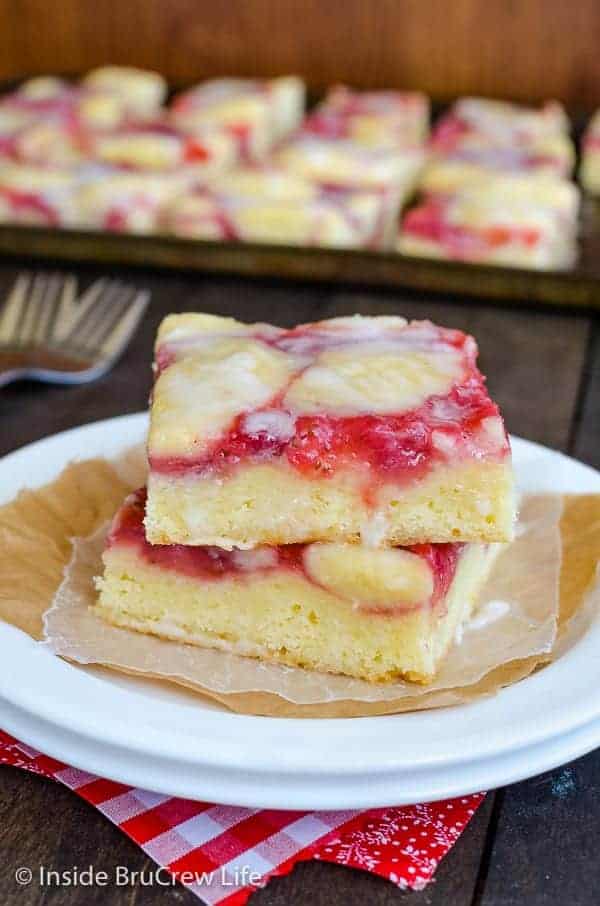 A white plate with two squares of strawberry lemon cake stacked on it