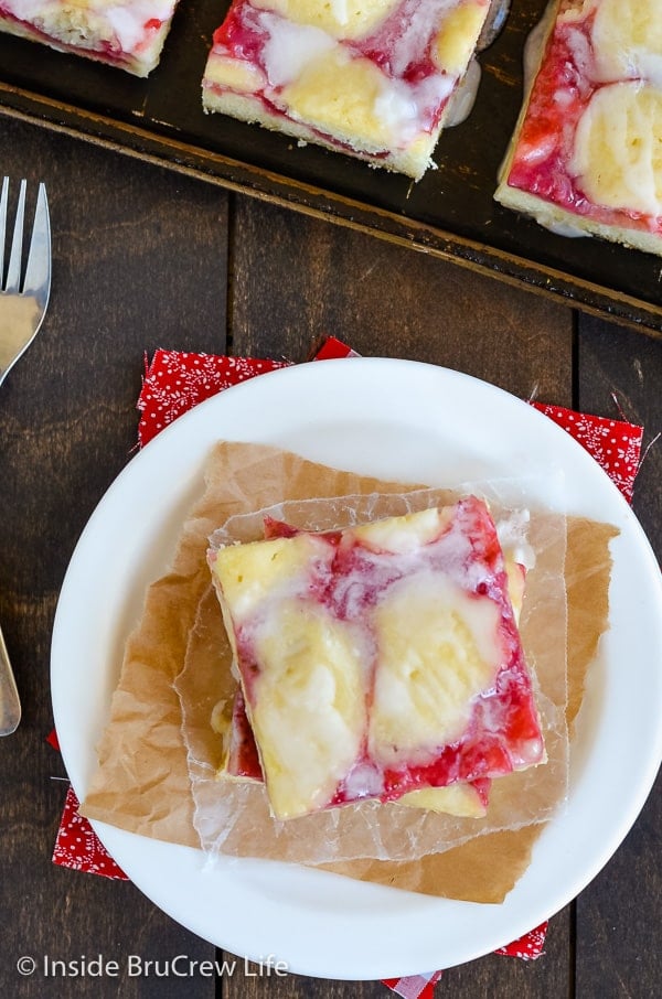 Overhead picture of a white plate and cookie sheet with squares of strawberry lemon cake on them