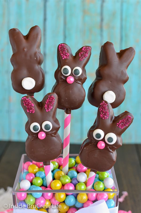 Jar of pastel Sixlets with chocolate covered marshmallow bunnies on pink and white straws.