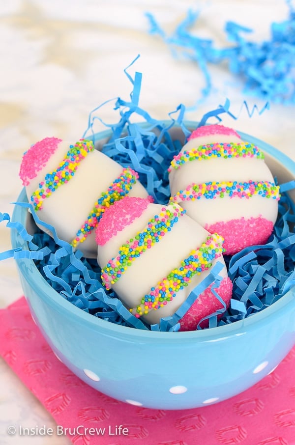 A blue bowl with blue filler paper and three white chocolate Nutella eggs inside it.