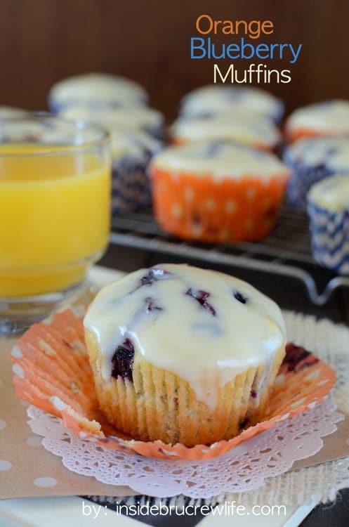 A glazed blueberry muffin with a glass of juice.