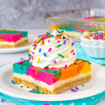 A white plate with a rainbow vanilla cheesecake with Cool Whip and sprinkles on top