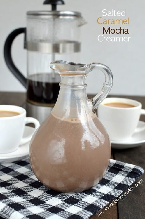A jar of homemade salted caramel mocha creamer on a black and white towel with a cup of coffee behind it