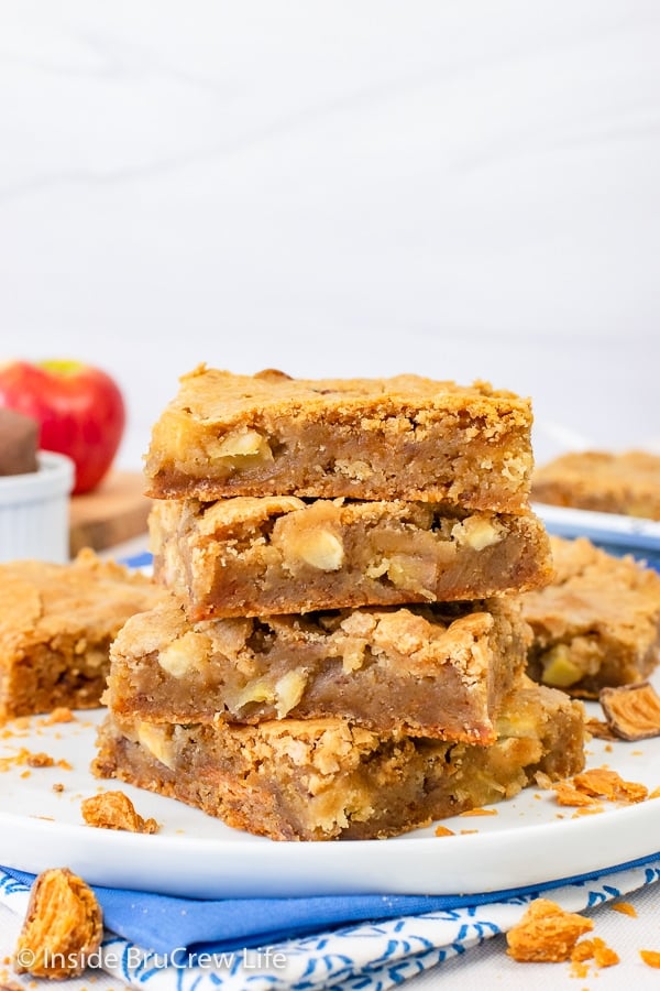 Four apple blonde brownies stacked on a white plate.