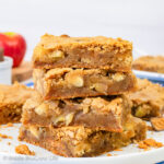 A stack of four apple blondies on a white plate.