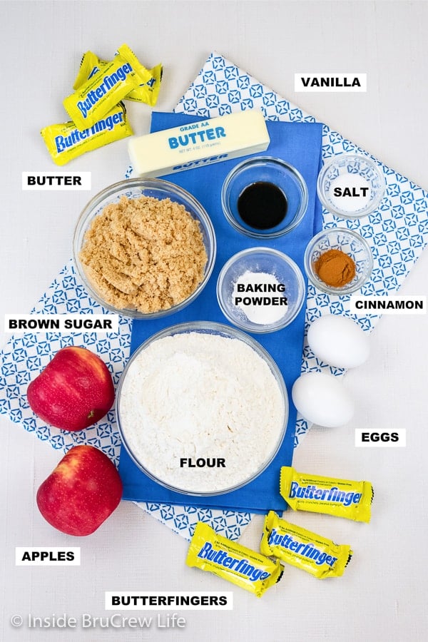 White board with bowls of ingredients needed to make a pan of apple blondies with apples and Butterfingers.