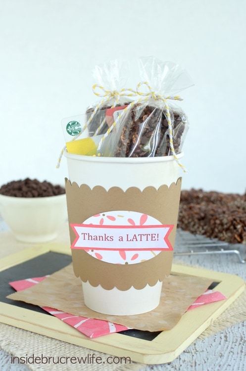 A white cardboard coffee cup stuffed with cappuccino chip granola bars and a coffee gift card