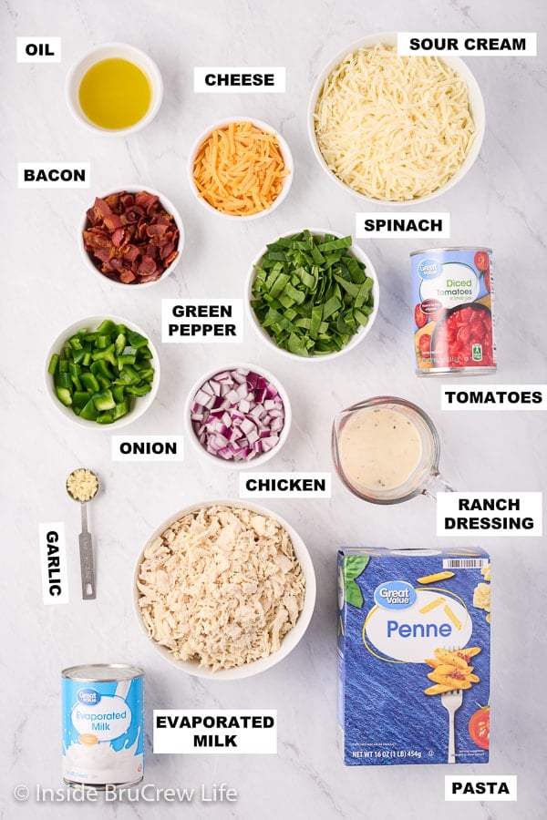 A white board with bowls of ingredients needed to make a bacon ranch pasta recipe.