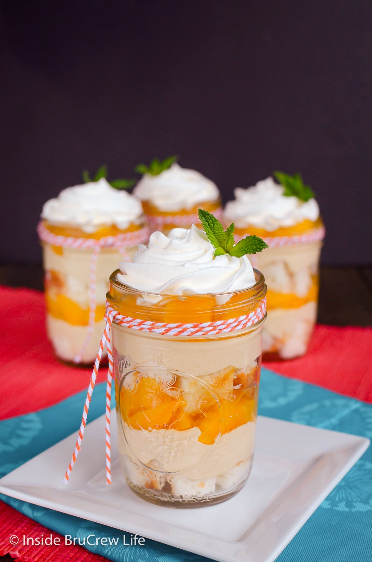 Four clear jars filled with cake, no bake cheesecake, and pie filling.